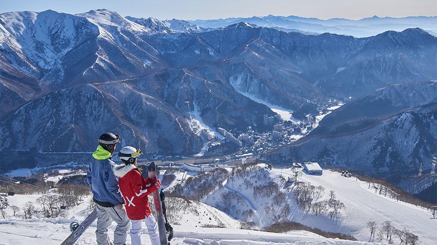 カップルが山頂からゲレンデを見ている。