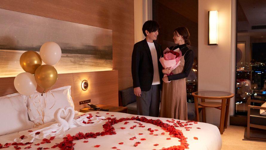 夜景をバックにバラの花束を抱えた女性と男性が見つめあう