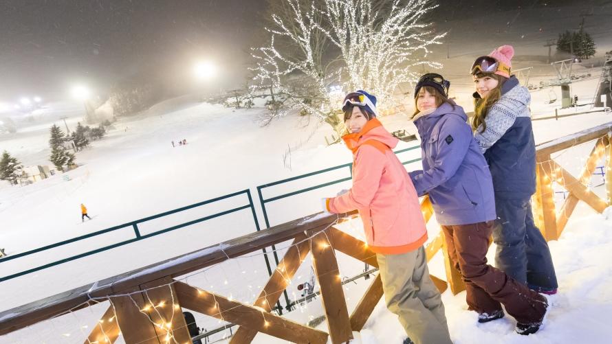 女性3人がゲレンデで笑顔で写真を撮っている。